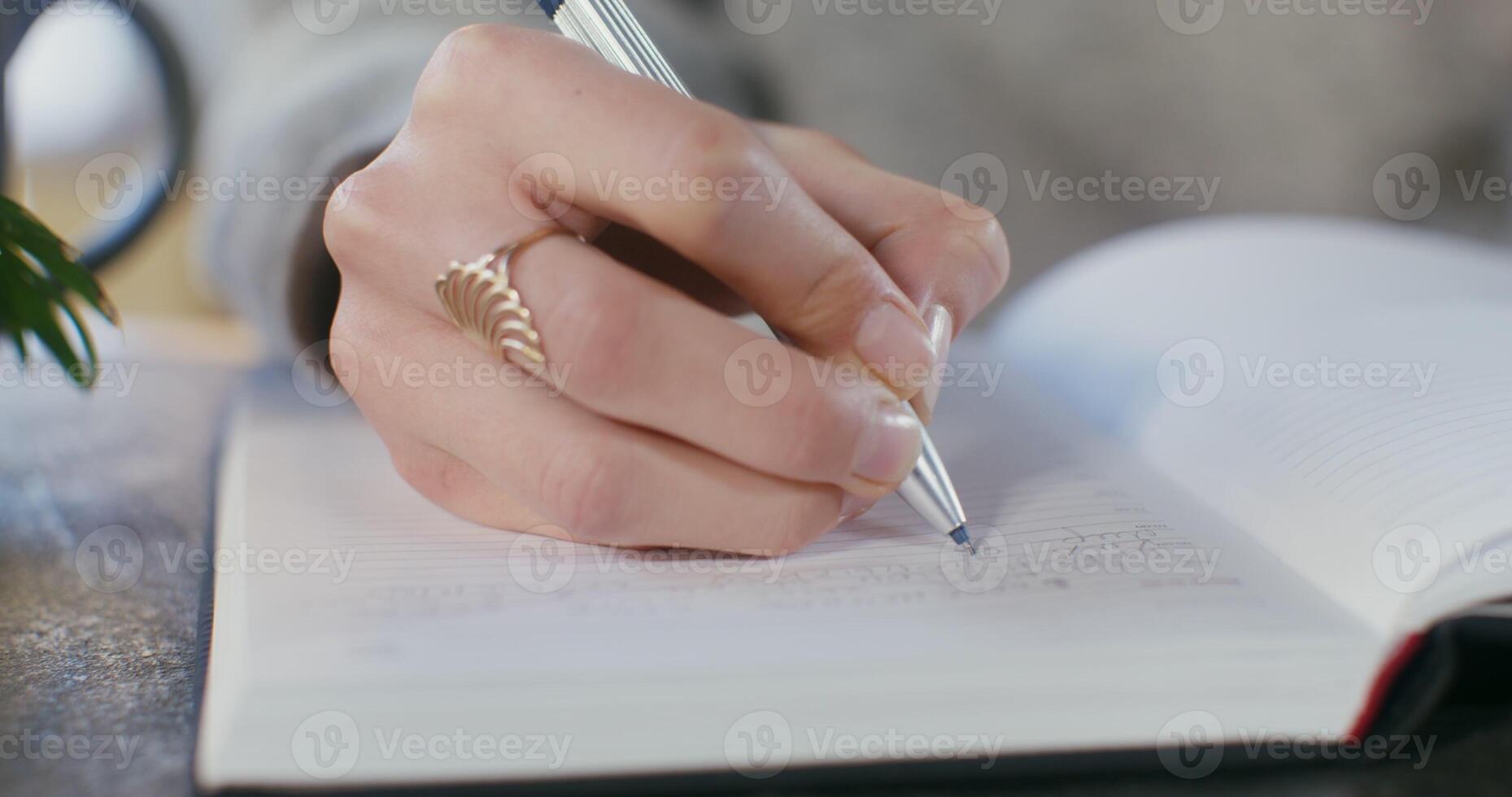 Close-up of a writing with a pen in a notebook female hand photo