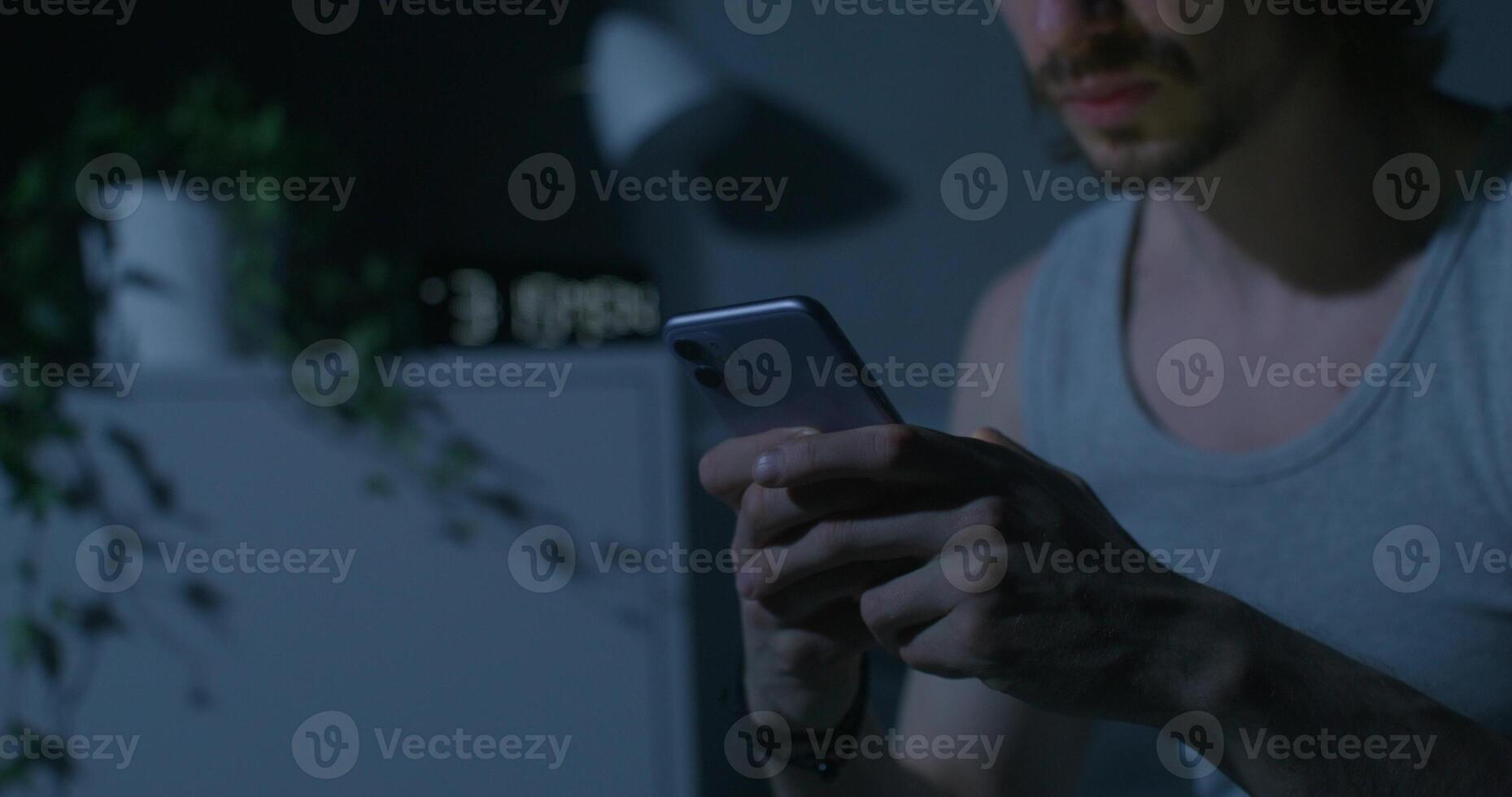 A man in a tank top is using his phone photo
