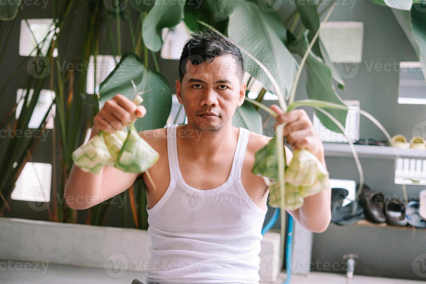 Man Displays Ketupat, a Traditional Indonesian Rice Dumpling Treat photo