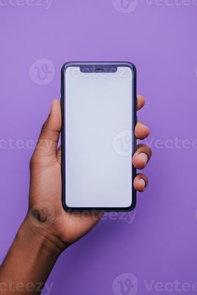 Hand holding a smartphone against a purple background, showcasing a blank screen for creative content photo