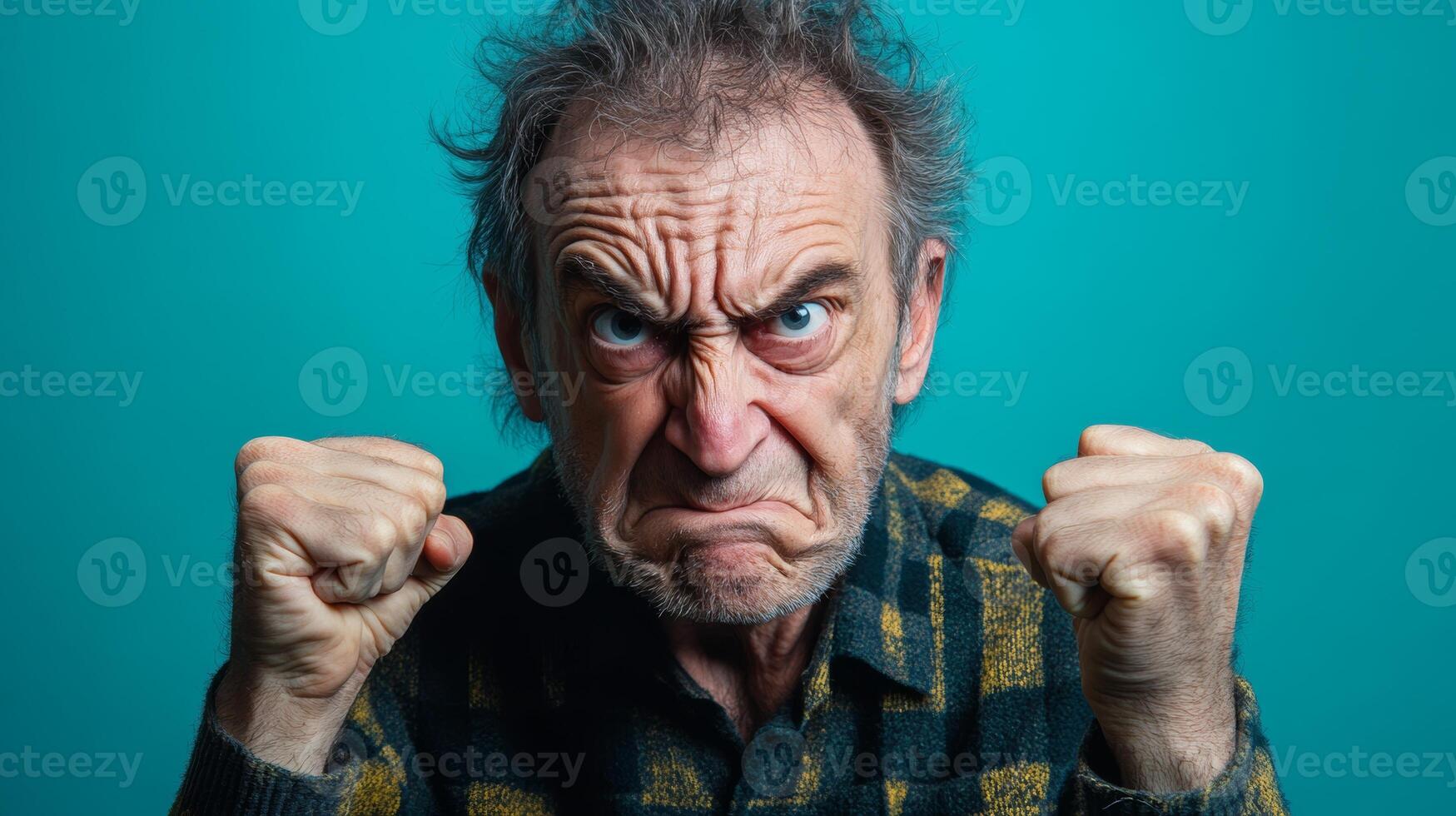 Angry elderly man expressing frustration in front of a teal background during daylight photo
