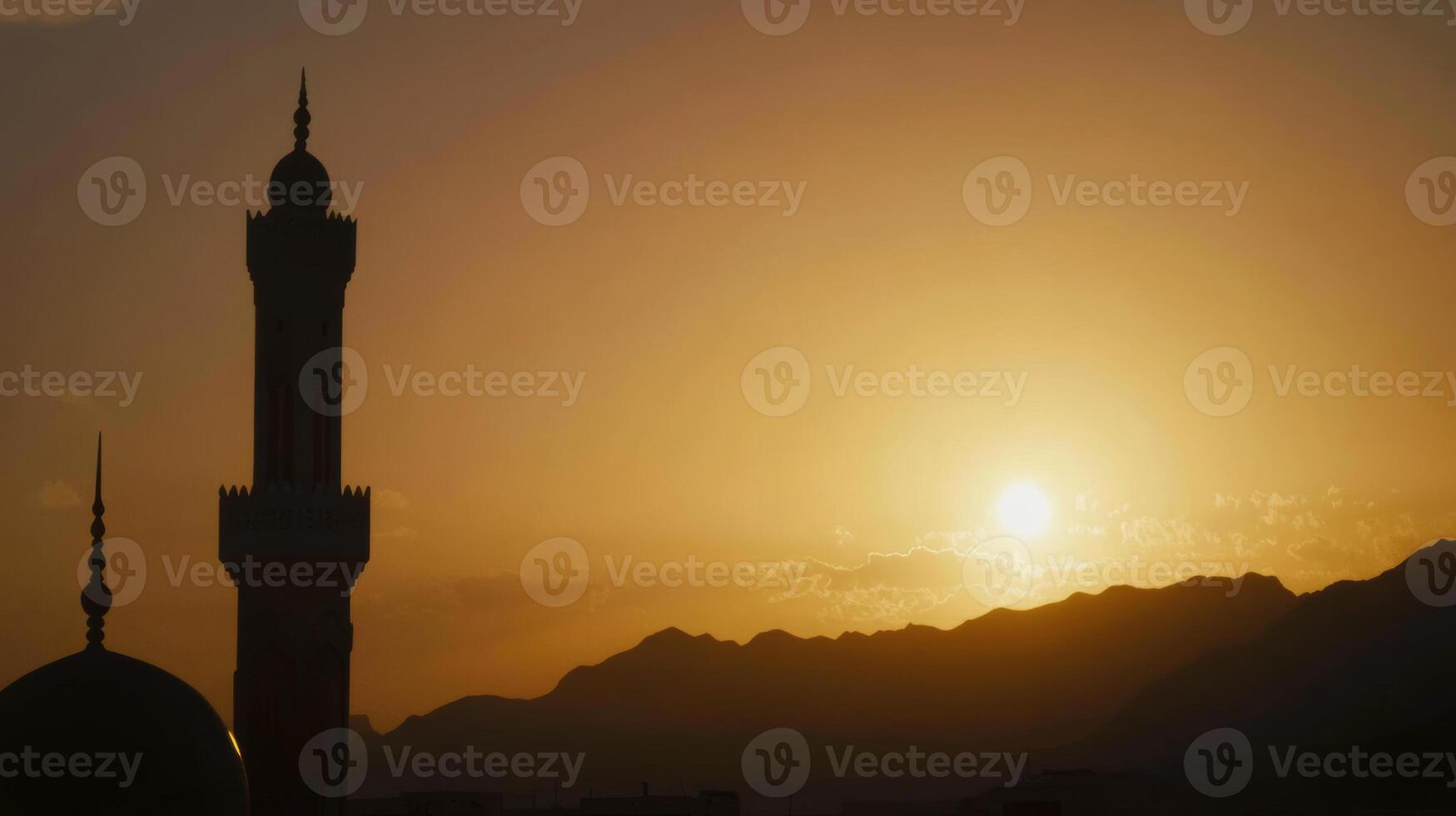 Sunset over a mosque and mountains creating a serene atmosphere in the evening sky photo