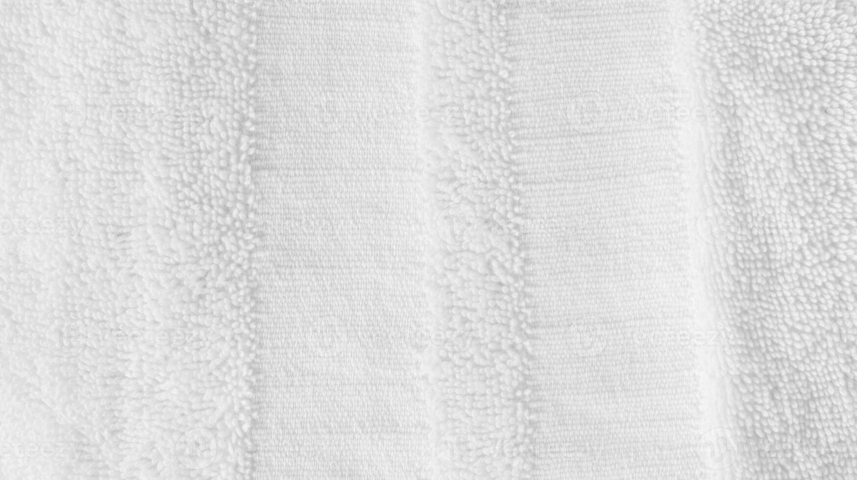 Soft and fluffy white towel hanging against a neutral background in a bright bathroom setting during daylight hours photo