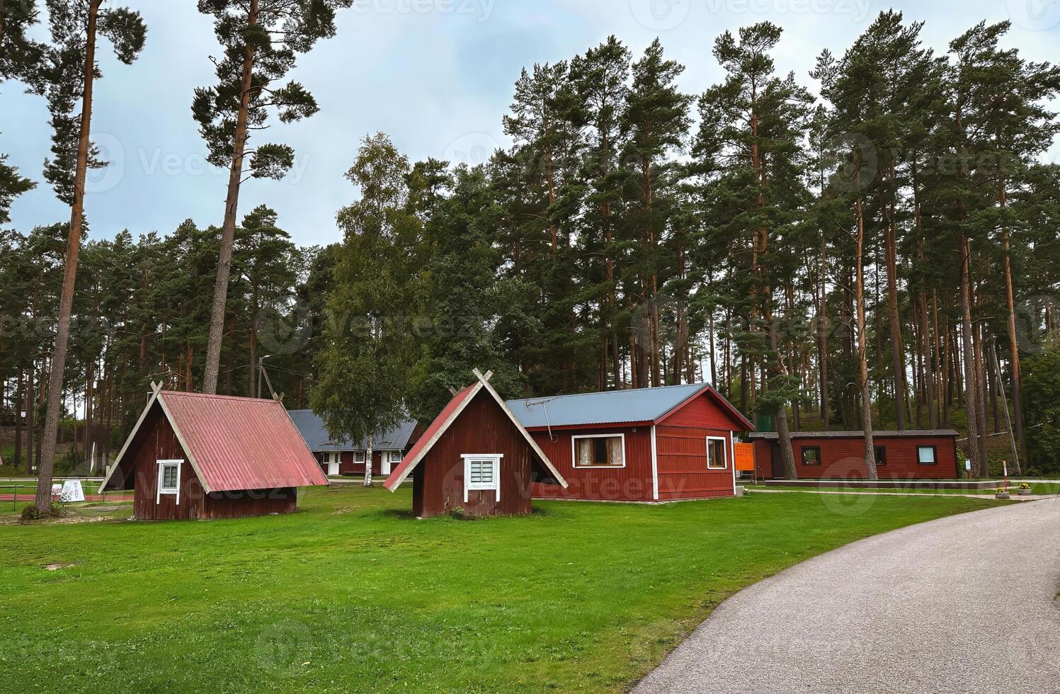 A row of small red houses are in a grassy field. photo