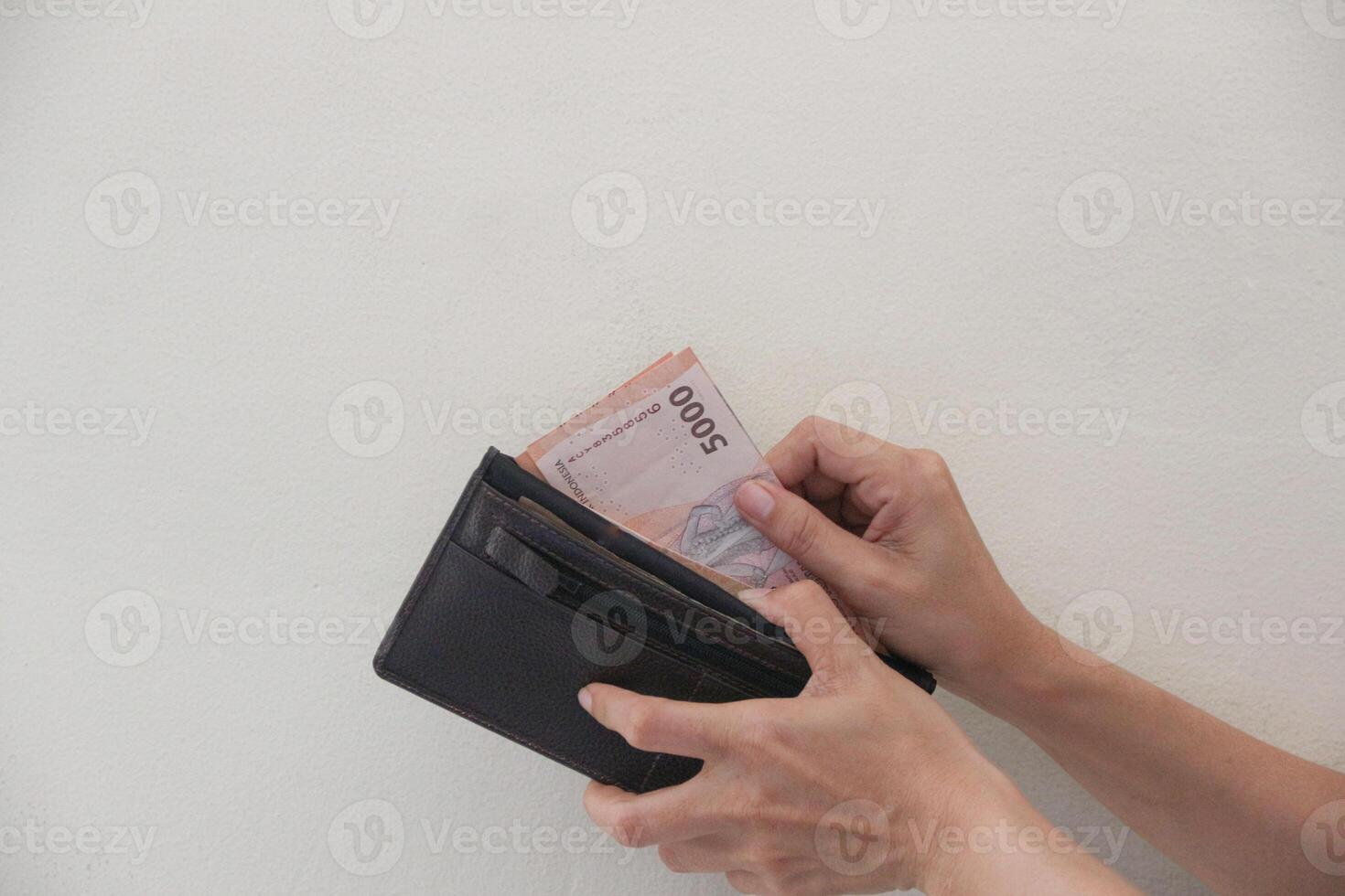 Hand taking rupiah money from brown wallet isolated on white background photo