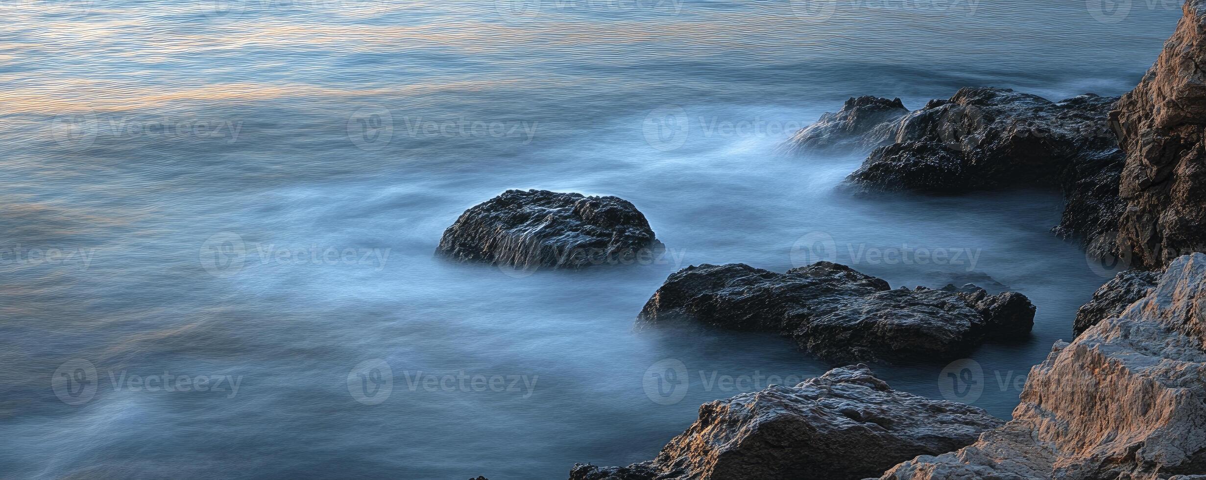 A person is sitting on a rock in the ocean photo