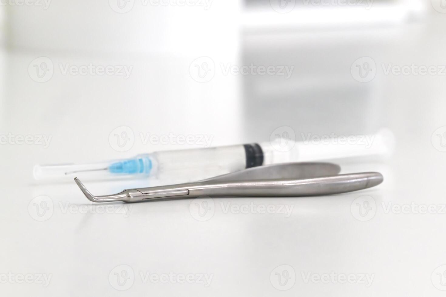 A close-up of dental tools including a dental scaler and a syringe on a clean surface, suggesting a dental or medical setting. photo