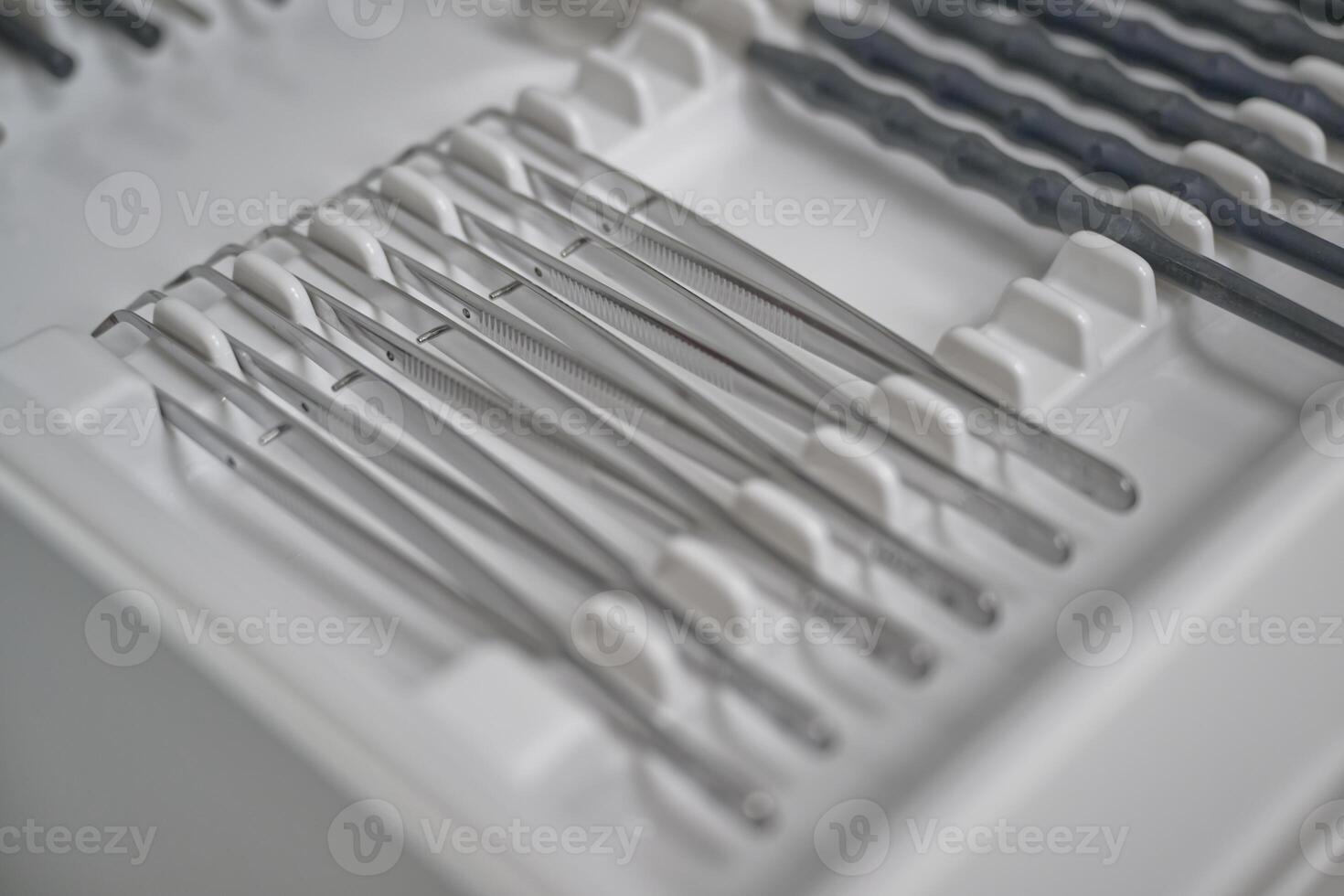 A close-up view of a set of surgical instruments neatly arranged in a tray. The instruments include various types of tweezers and scalpels. photo