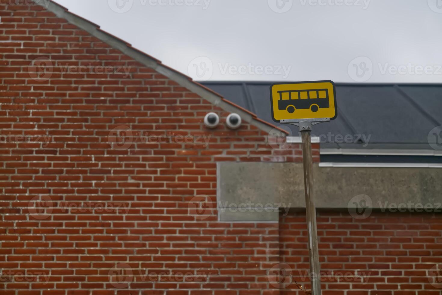 Bus Stop Sign in Front of Brick Building photo