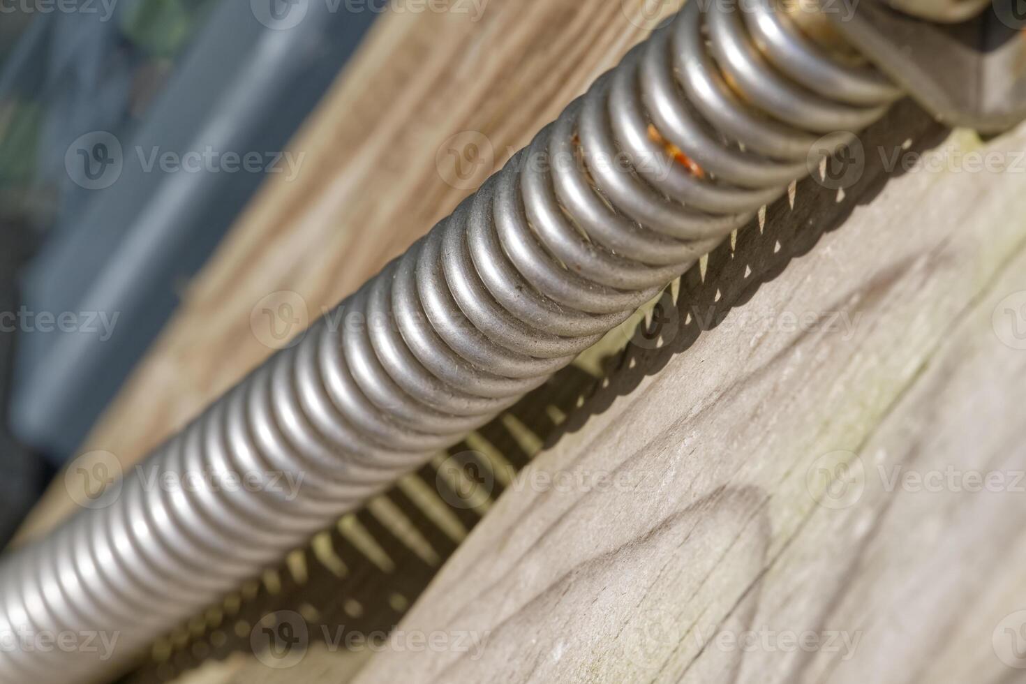 Close Up of a Metallic Coil Spring on Wood photo