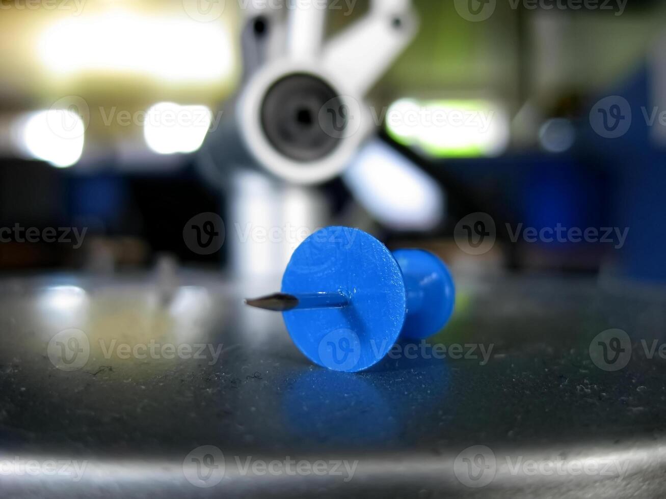 Close Up of a Blue Push Pin on Metallic Surface photo