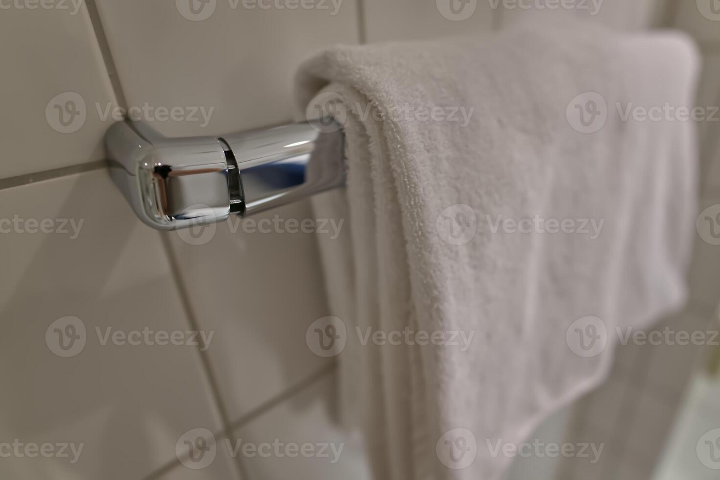 White Towel on Chrome Rack in Bathroom with white tiles photo