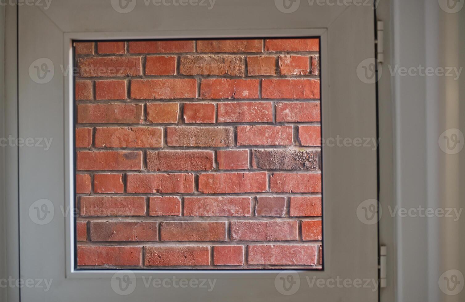 View of Red Brick Wall Through Window Frame photo
