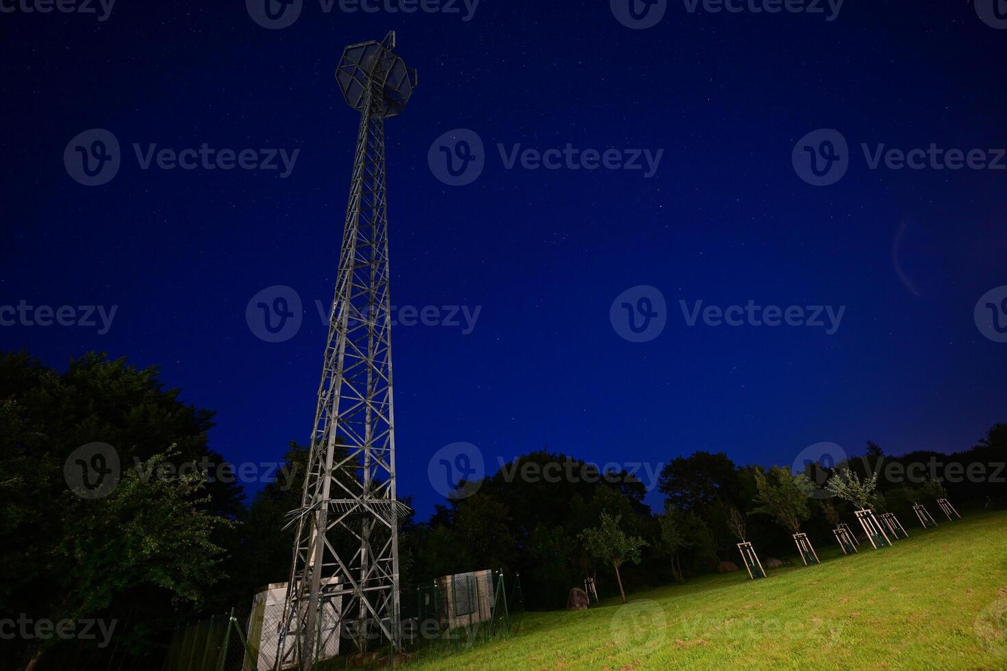 Night View of a Communication Tower in a Grassy Field photo