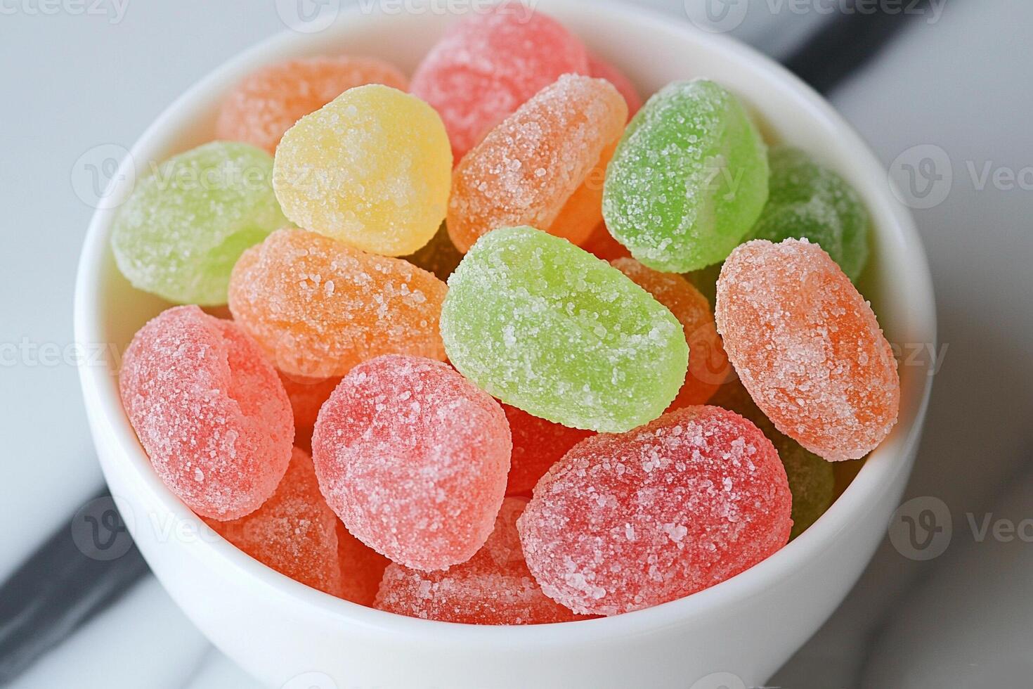 A bowl of colorful gummy bears on a marble surface photo