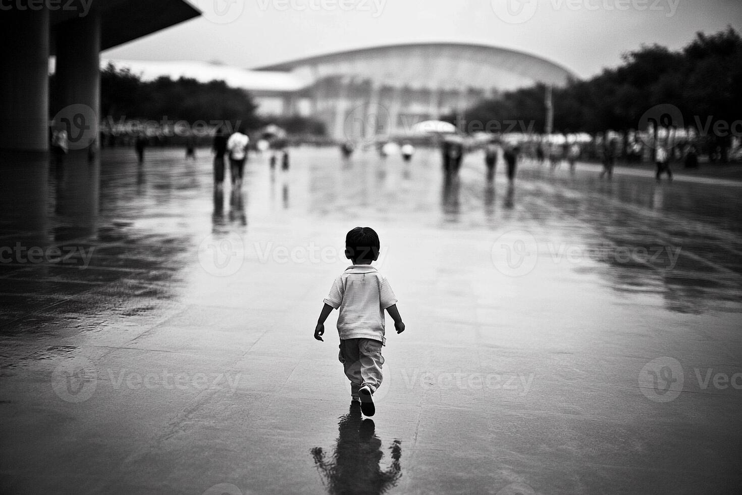A young boy walking through the rain in front of an arena photo