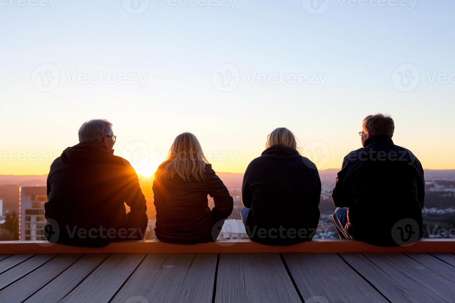 Three people sitting on a bench looking at the sunset photo