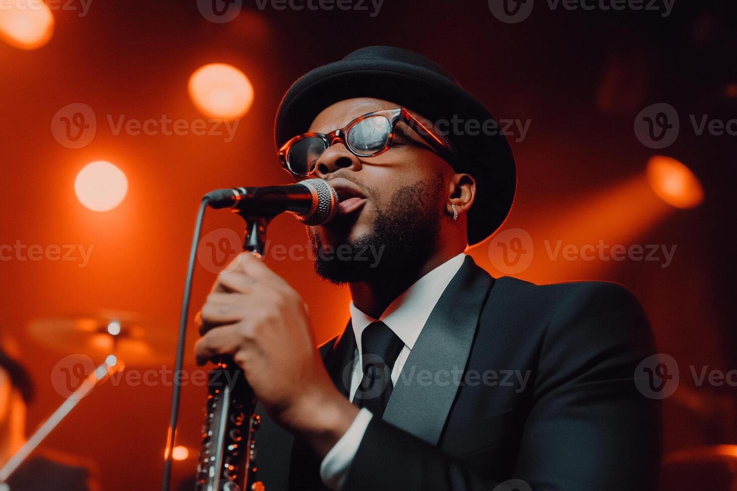 A man in a suit and hat singing into a microphone photo