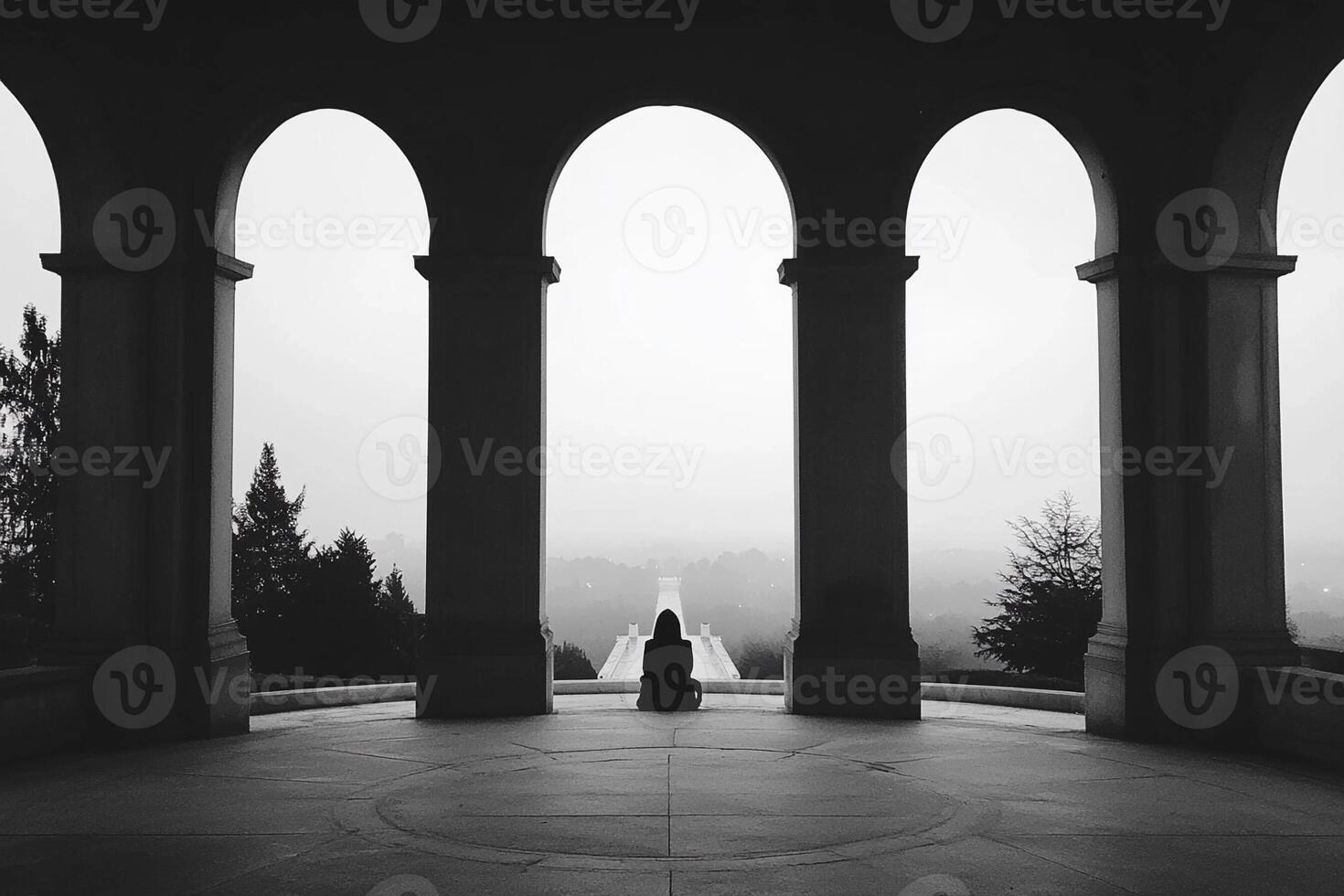 A person sitting in an arched doorway looking out over a valley photo