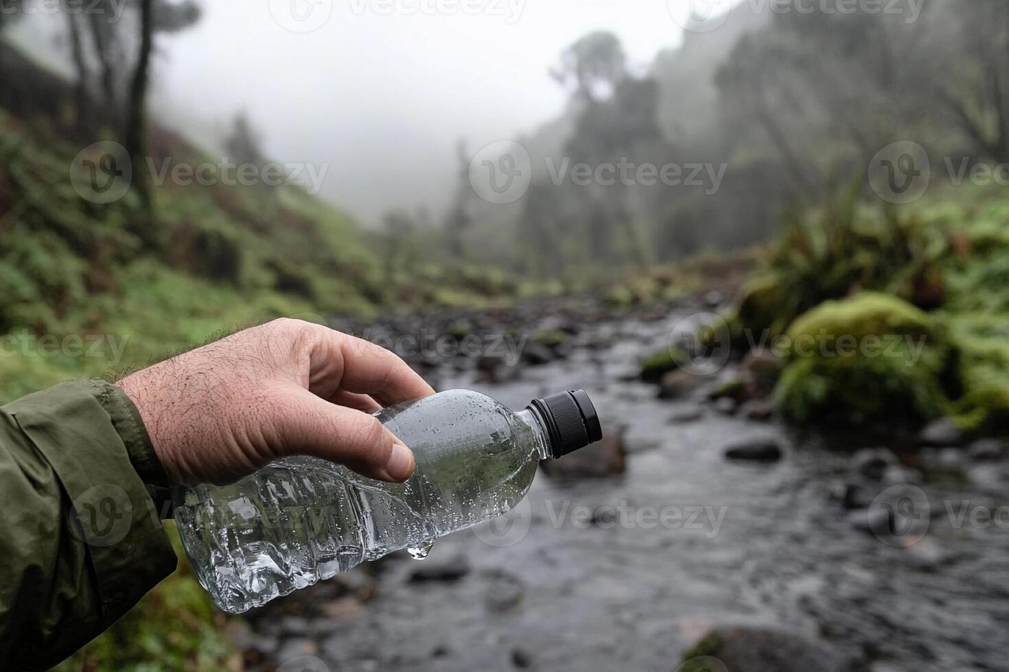 A person holding a plastic bottle in front of a stream photo