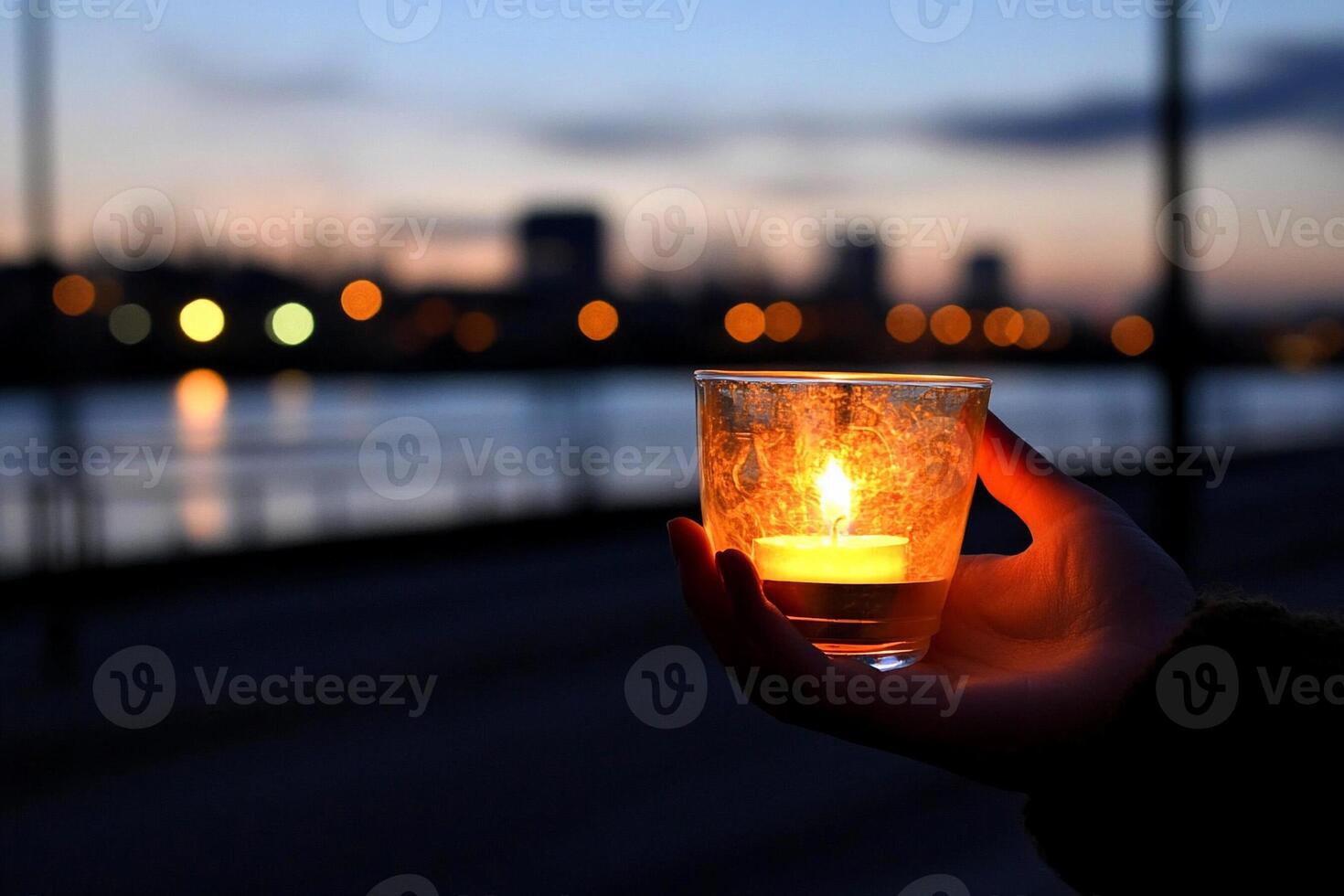 A person holding a candle in front of a river photo