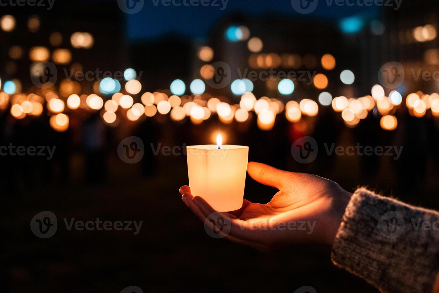 A person holding a lit candle in front of a crowd photo