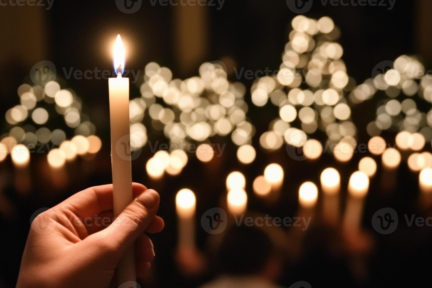 A person holding a lit candle in front of a crowd of people photo