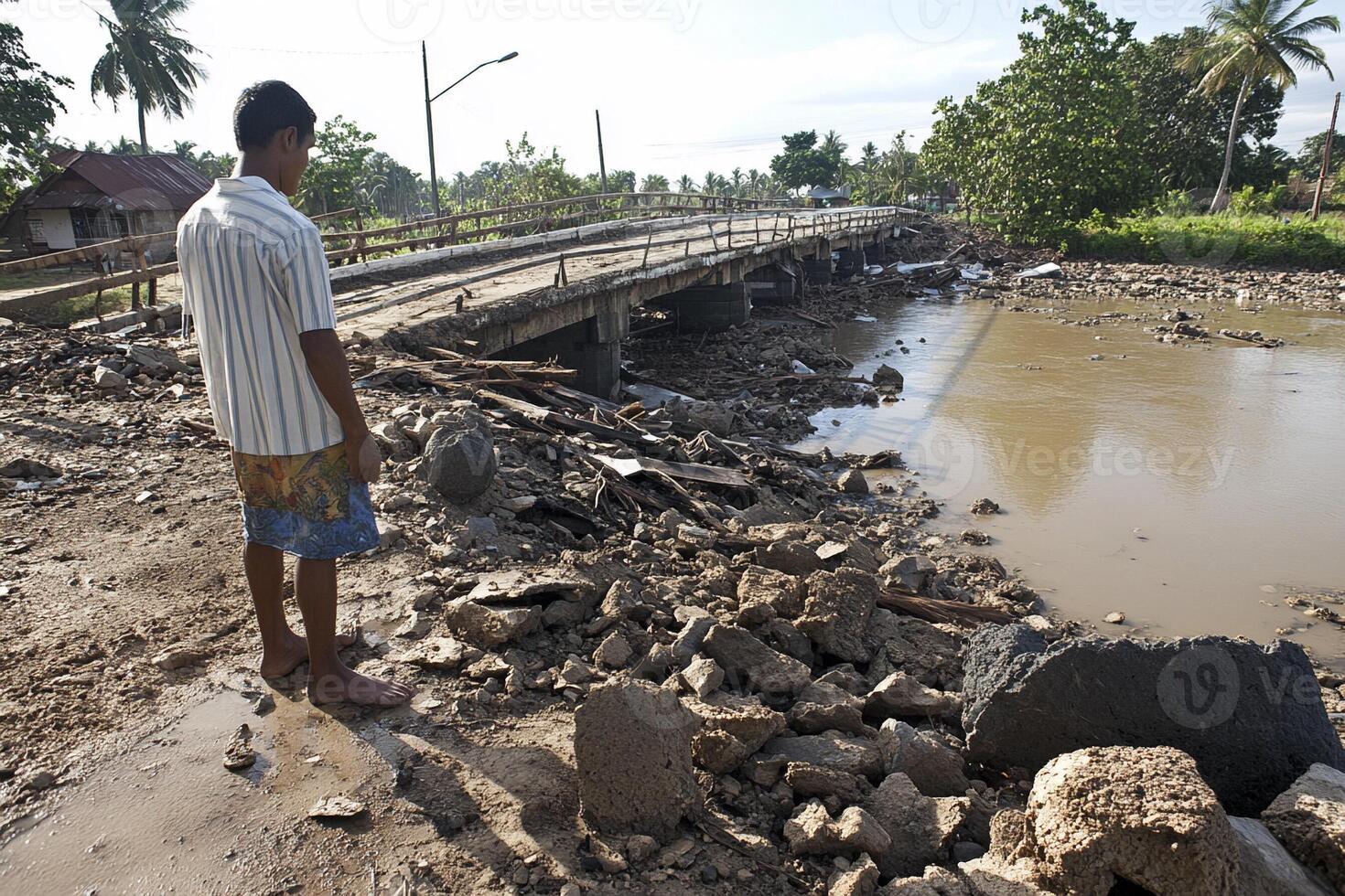 A man stands on a bridge over a river in the middle of a mudslide photo