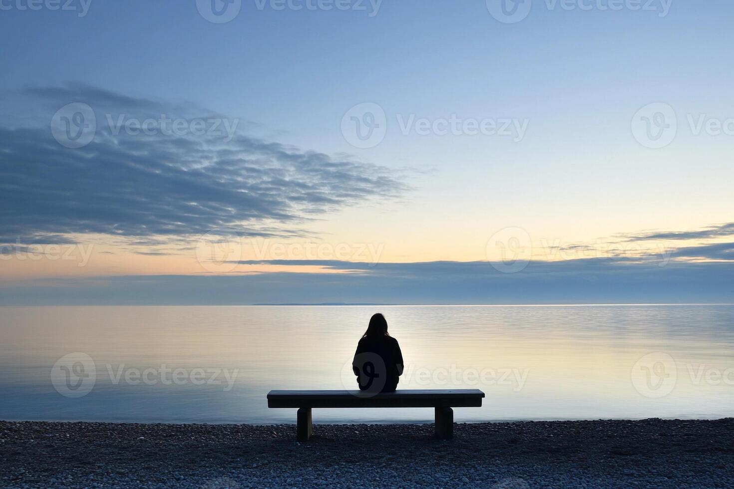A person sitting on a bench looking out over the ocean photo