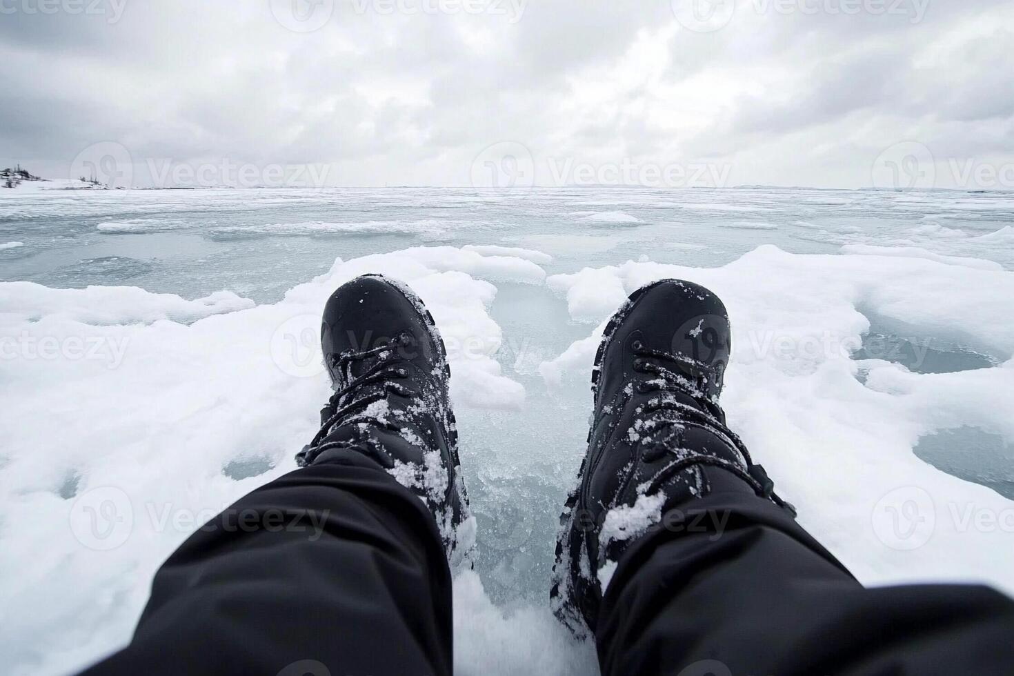 A person wearing black boots on top of ice photo
