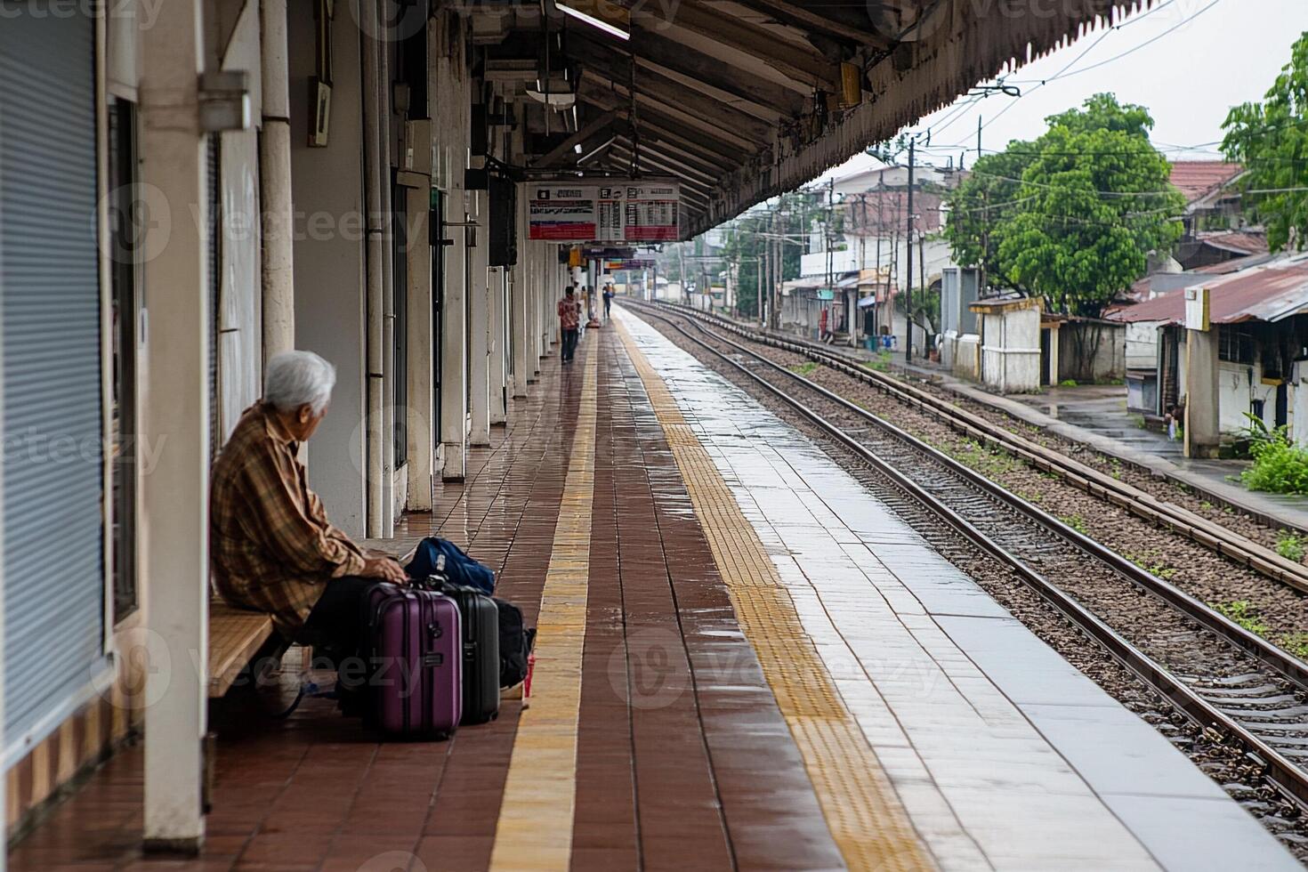 A woman sitting on a bench waiting for a train photo