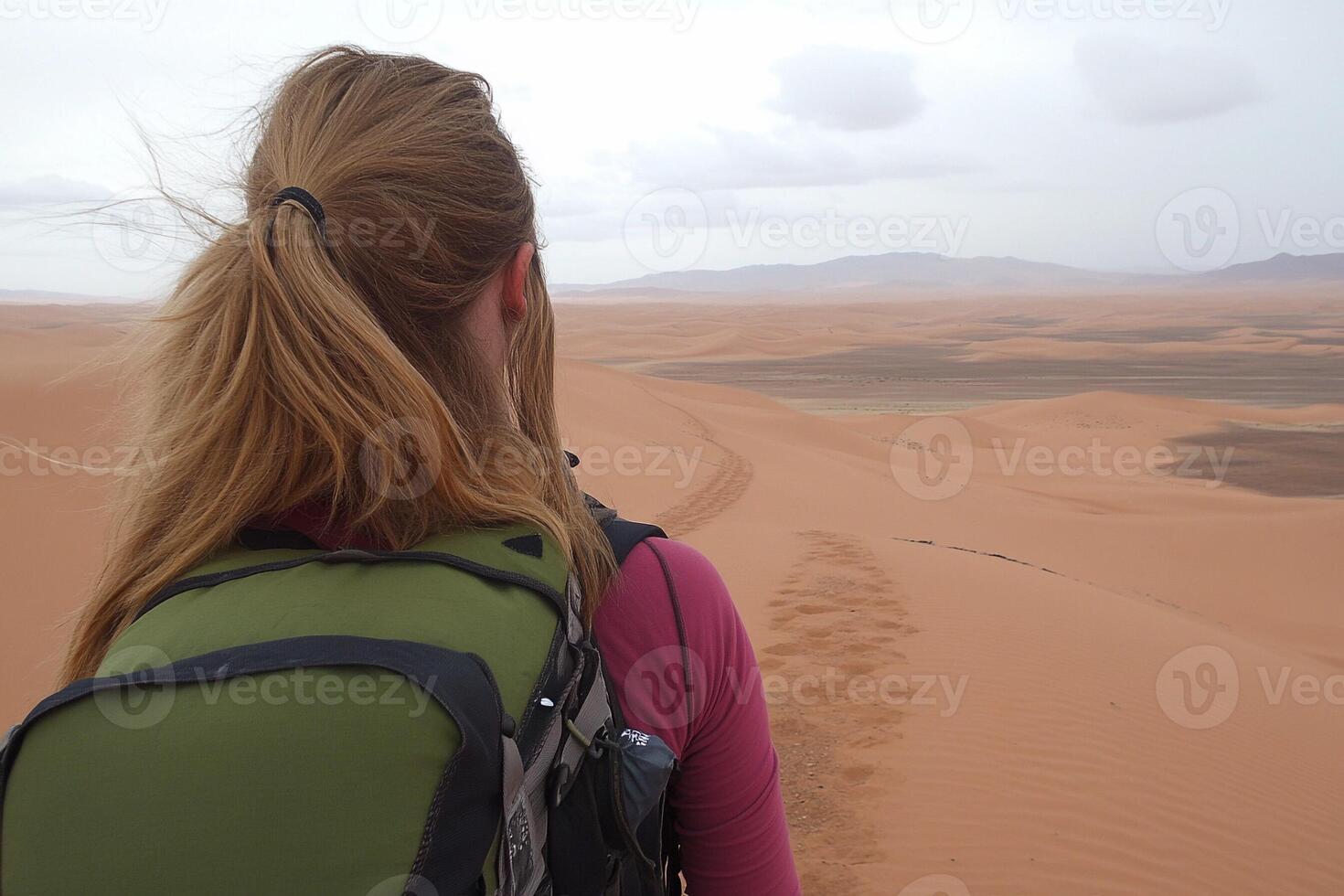 A woman with a backpack walking through the desert photo