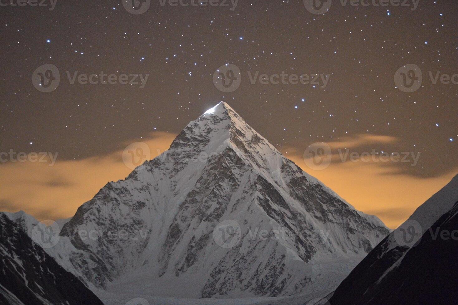 A mountain peak is lit up by the stars photo