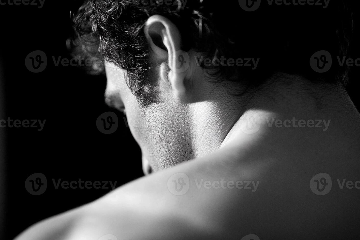 A man with no shirt on looking down photo