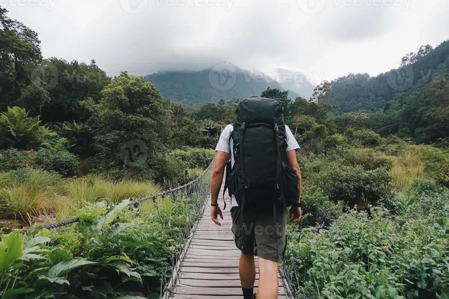 A man with a backpack walking across a wooden bridge photo