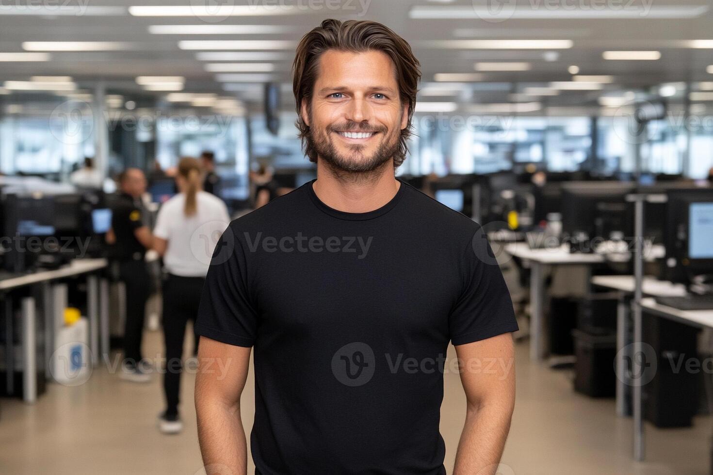 A man in a black t - shirt standing in an office photo