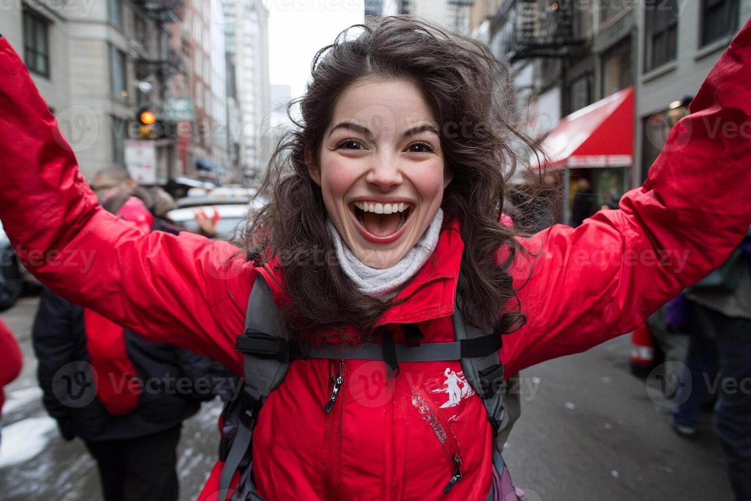 A woman in a red jacket is smiling and holding her hands up photo