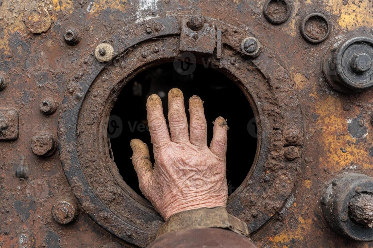 A person's hand reaching through a hole in a rusty door photo