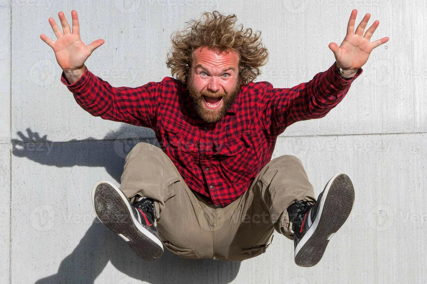 A man with a beard and red shirt is jumping on a skateboard photo
