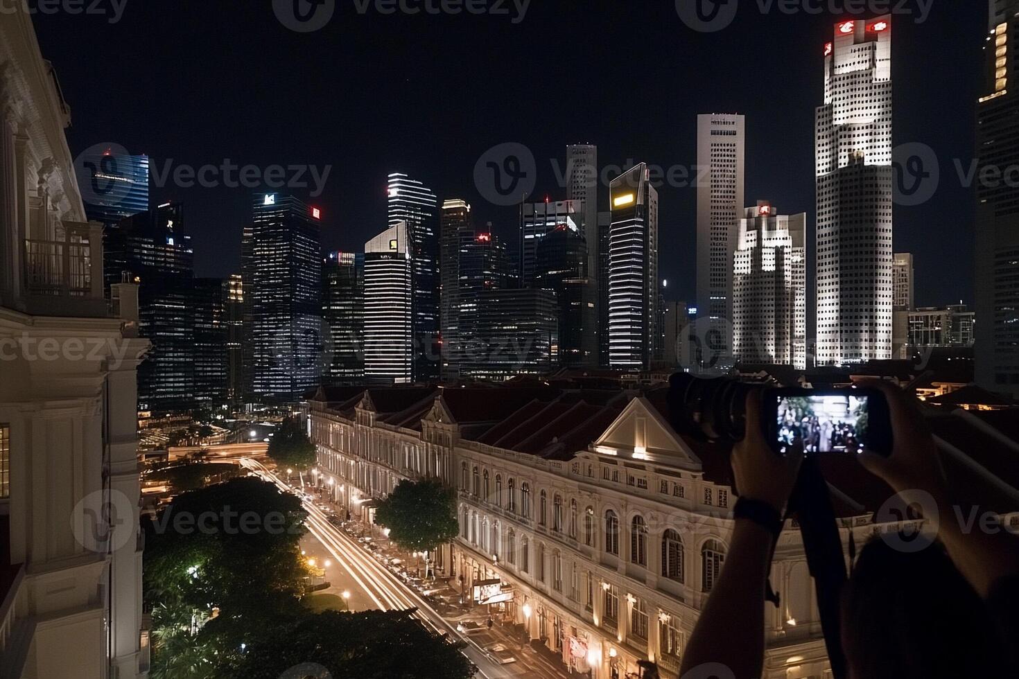 A person taking a picture of the city at night photo