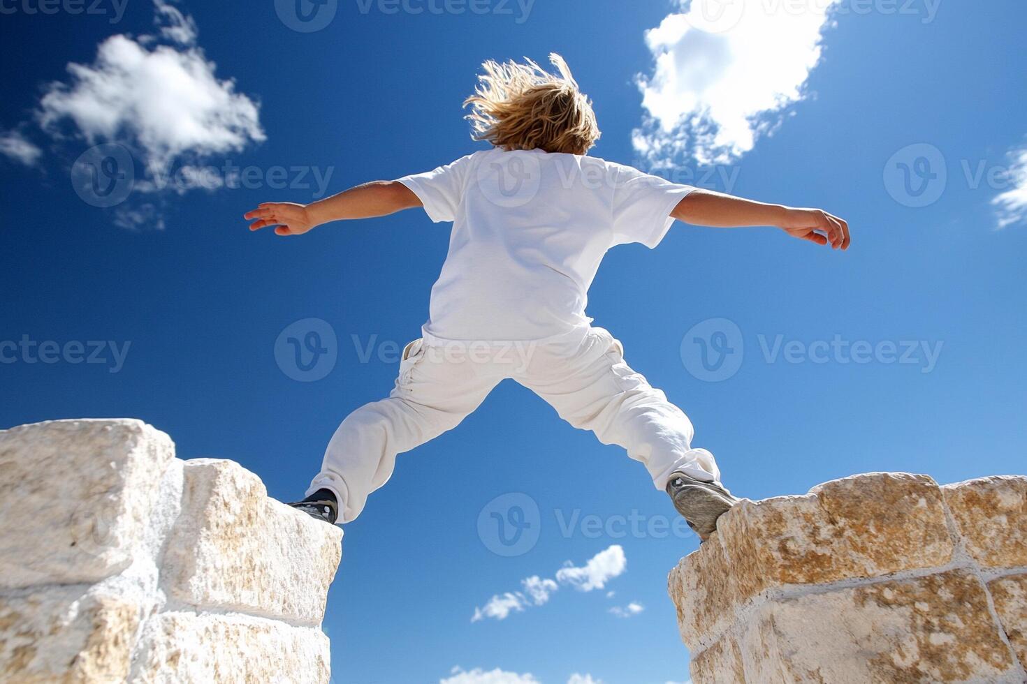 A young boy is jumping over a wall photo