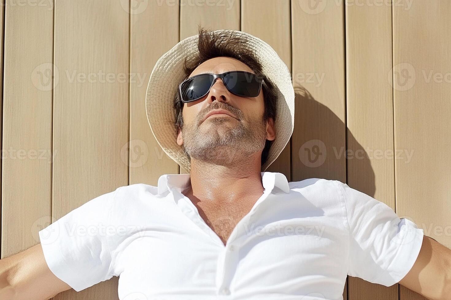 A man in a white shirt and sunglasses laying on a wooden floor photo