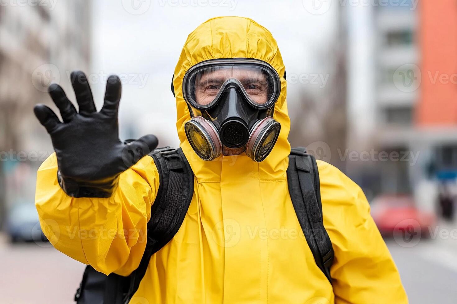 A man in a yellow gas mask and protective suit waving photo