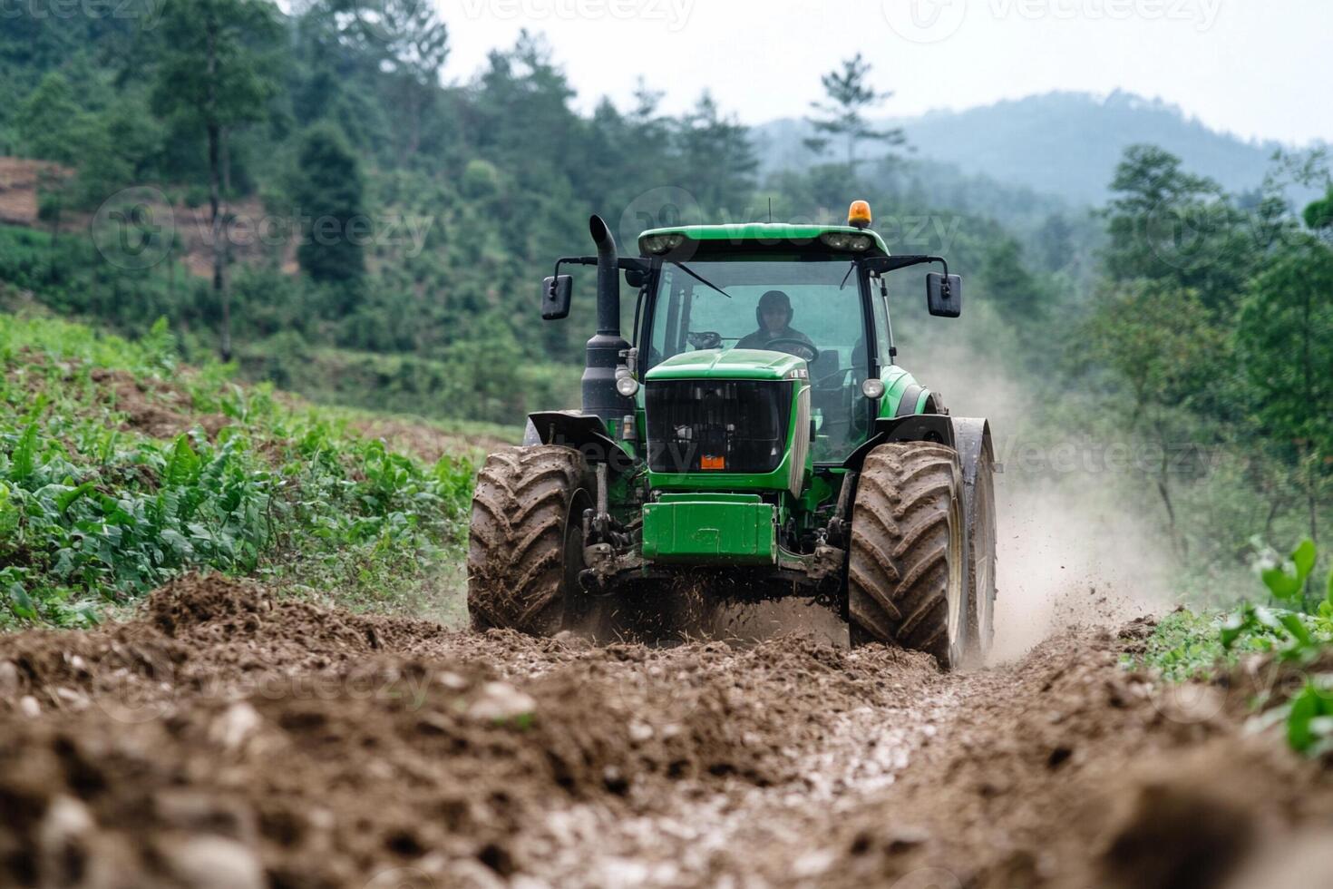A green tractor driving through a muddy field photo