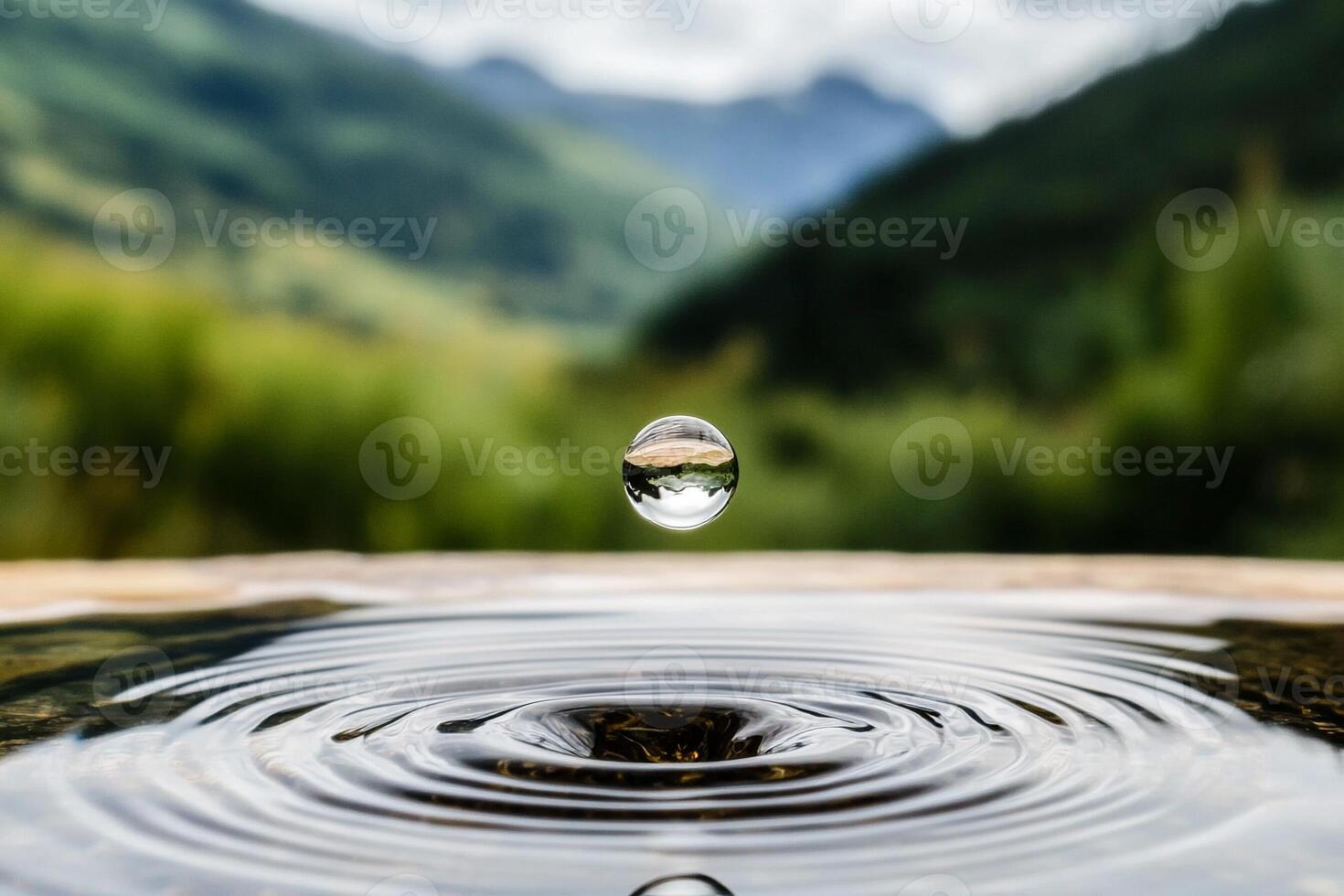 Water drop on a wooden table with mountains in the background photo