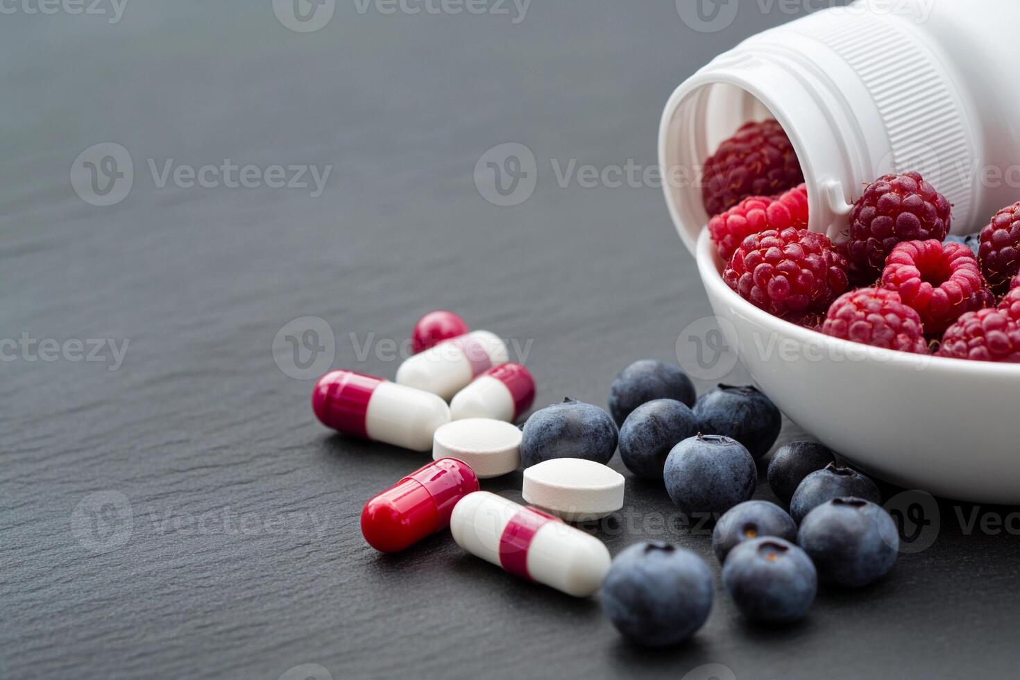 A white pill bottle with raspberries and blueberries photo