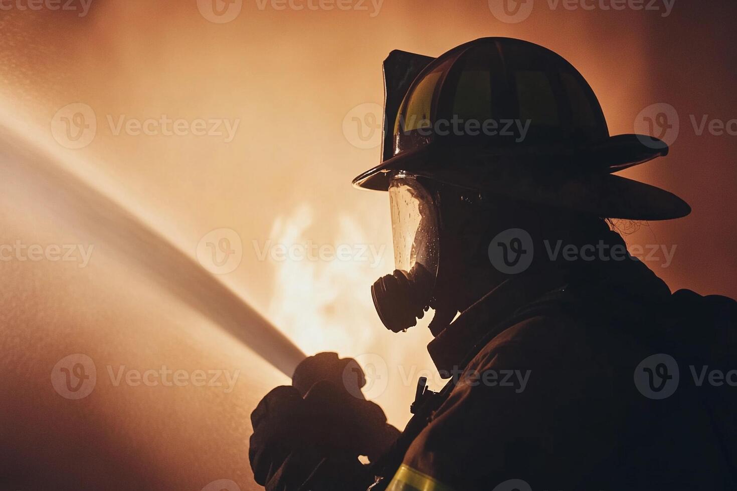 A firefighter with a hose in front of a fire photo