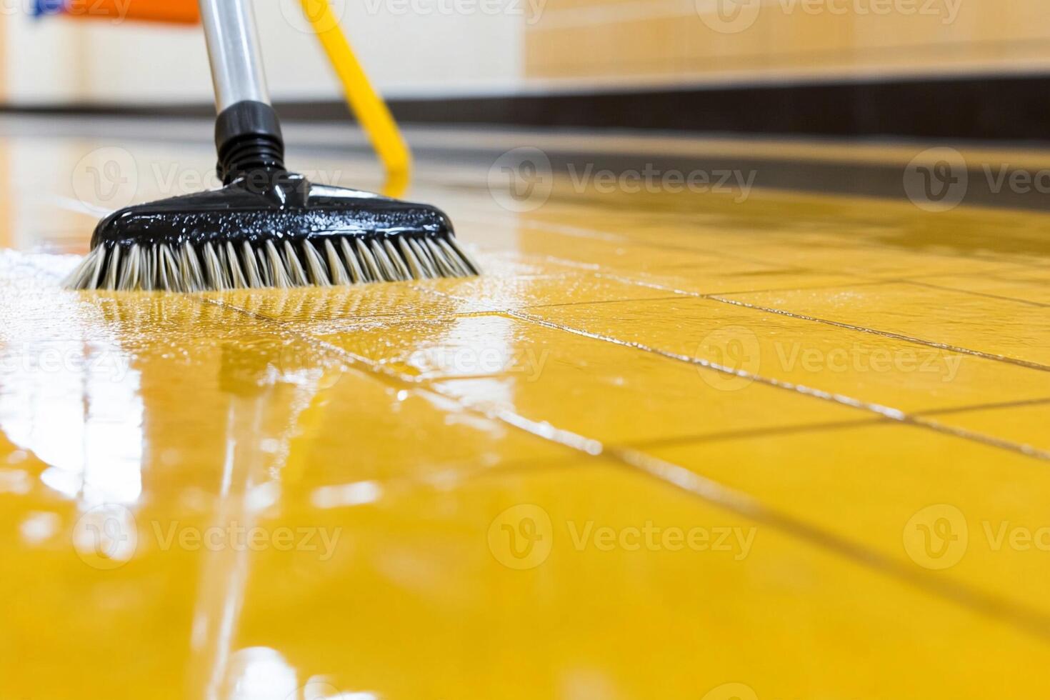 A person cleaning a yellow tile floor with a broom photo