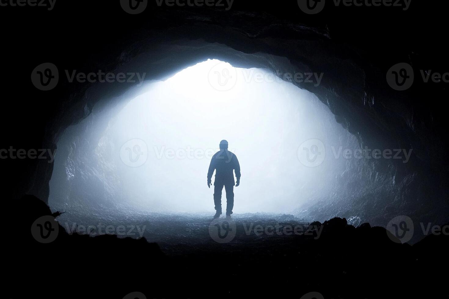 A man standing in front of a dark cave photo