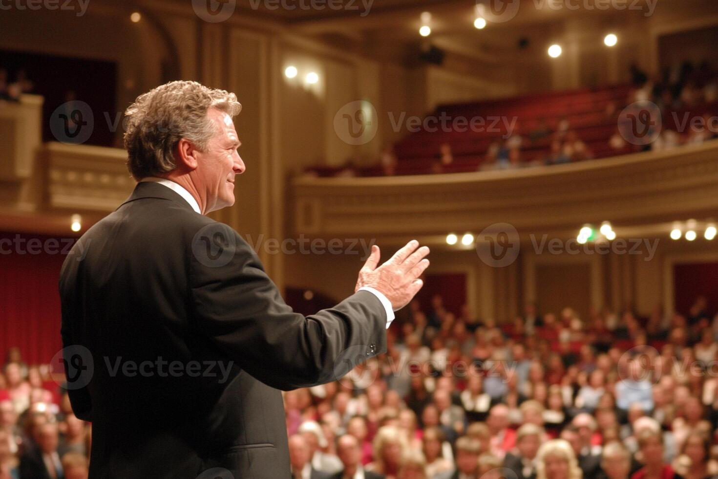 A man in a suit is speaking to a crowd photo